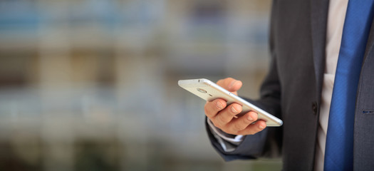 Man holding phone. Young businessman in business wear using a mobile, closeup view on smartphone, banner