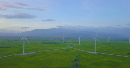 Fototapeta na wymiar Wind turbine farm and agricultural fields on a summer day. High-quality stock photo picture wind turbine in a green field - Energy Production with clean and Renewable Energy. Phan Rang, Vietnam