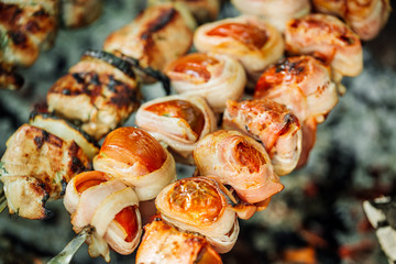 Grilled tomato and bacon skewers in a herb marinade on a grill, top view