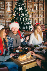 Friends having dinner at home at Christmas eve. Winter holidays concept.