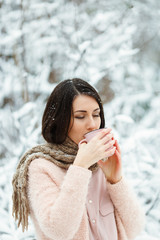 girl with a pink cup of coffee in the winter forest