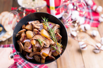 Russian salad and fried potatoes with mushrooms and meat on a wooden table. Delicious traditional winter food in Russia. Celebration of Christmas and New Year. Free space for text.