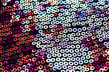 textured background of shiny round multicolored iridescent sequins sewn on fabric for a trendy festive evening dress