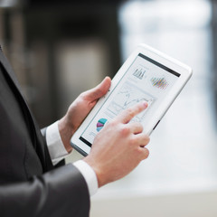 Business person analyzing financial statistics displayed of the tablet screen