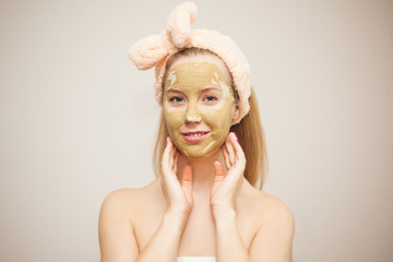 A young woman makes a face mask from clay. Cosmetic procedures. Home skin care.