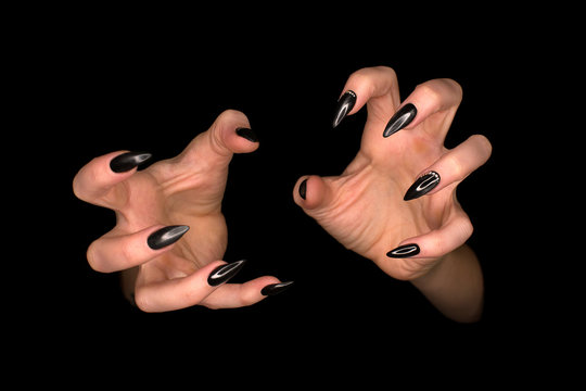 Gothic manicure, female hands with sharp black glossy nails, isolated on black background, close up, low key