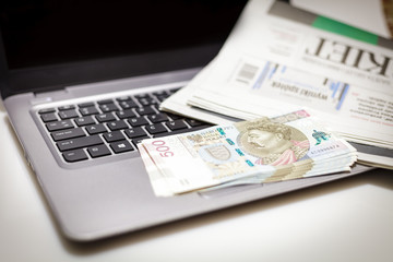 Biznes - plik banknotów 500 PLN na laptopie w towarzystwie gazety finansowej - obrazy, fototapety, plakaty