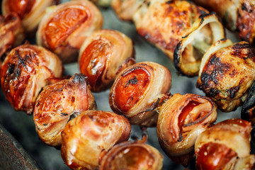 Grilled tomato and bacon skewers in a herb marinade on a grill, top view