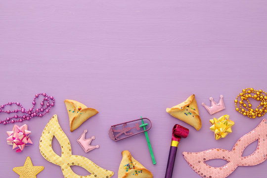Purim celebration concept (jewish carnival holiday) over pink, purple wooden background. Top view.