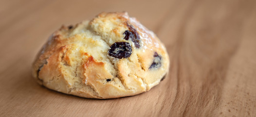 Bun with raisins on a wooden table.
