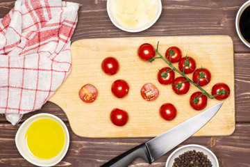 Cherry tomatoes slicing step. recipe step by step arugula salad on chopping board flatlay on brown wood