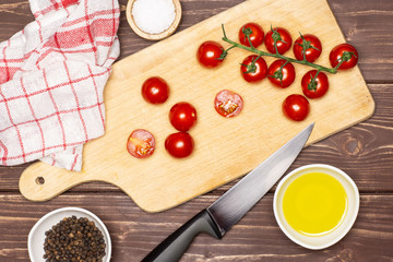 Slicing cherry tomatoes step. recipe step by step arugula salad on chopping board flatlay on brown wood
