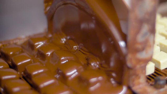 production, candy shop and industry concept - marzipan bars processing on chocolate coating machine at confectionery