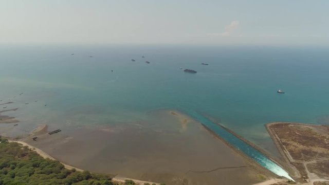 power station by sea with spillway into sea, barges full coal. paiton java, indonesia
