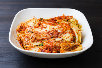 kimchi in white bowl on dark brown wooden board