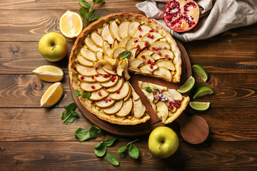 Wooden board with tasty homemade apple pie on table