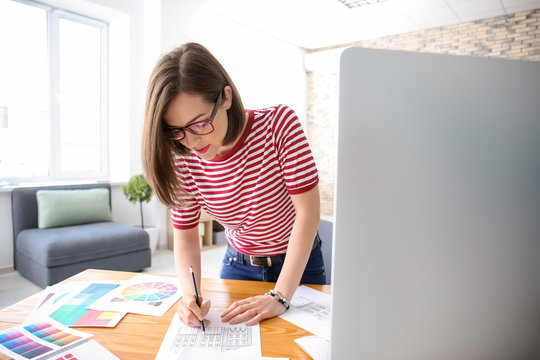 Beautiful young designer working in office