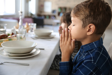Little boy praying before meal at home