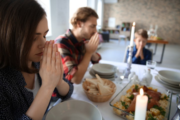 Family praying before meal at home