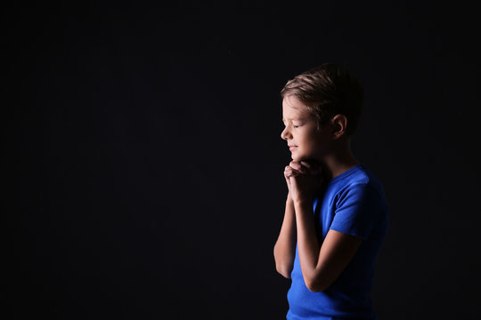 Portrait of praying boy on dark background