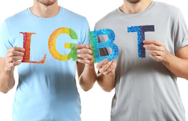 Fototapeta na wymiar LGBT couple holding rainbow letters on white background