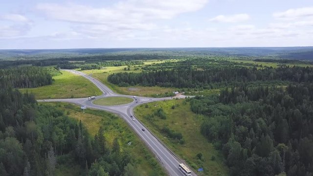 Top view of rural roundabout with traffic. Clip. Beautiful landscape of forest horizon and rural intersection of roads in ring. Rules of road at roundabout