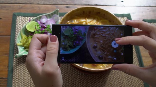 Taking Mobile Picture of Traditional Lanna Style Dish - Khao Soi Soup with Crispy Noodles. Food Photo of Authentic Nothern Thai Cuisine