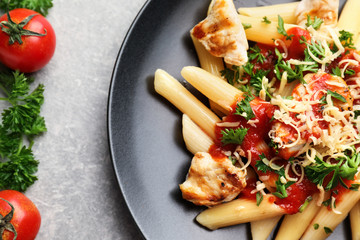 Plate with tasty penne pasta on grey table