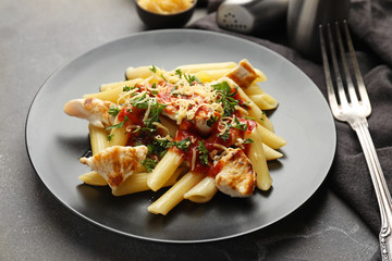 Plate with tasty penne pasta on grey table