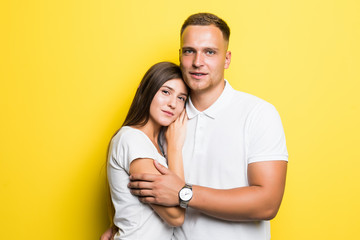 Portrait of happy lovely couple smiling and posing on camera together over yellow background