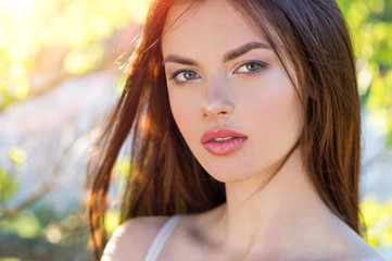 Closeup of girl posing outside in nature on a sunny day.