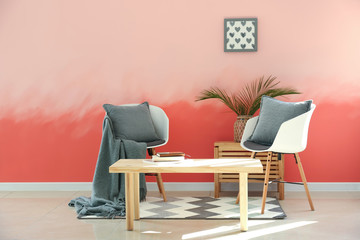 Interior of room with stylish furniture near pink wall
