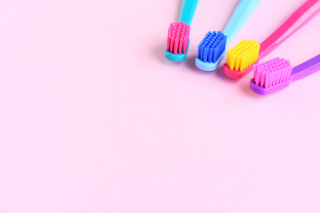 Four Colorful toothbrushes with selective focus on pink background. Toothbrush for personal routine morning  hygiene on neutral blurred backdrop. Dental plastic tool with empty space for image or text