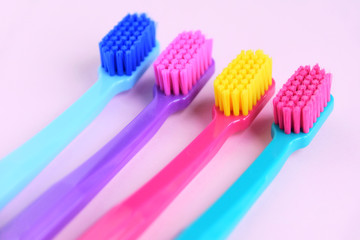 Four Colorful toothbrushes with selective focus on pink background. Toothbrush for personal routine morning  hygiene on neutral blurred backdrop. Dental plastic tool with empty space for image or text
