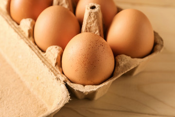 Carton box with raw chicken eggs on wooden table
