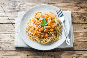 Spaghetti pasta Bolognese on white plate, wooden table