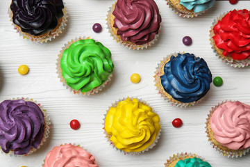 Colorful cupcakes on white wooden background