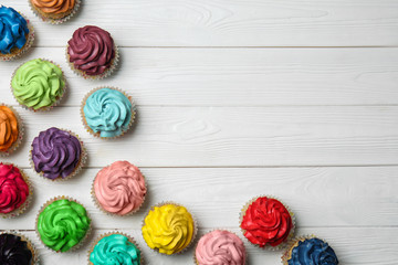 Colorful cupcakes on white wooden background