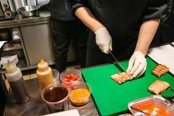 Chef cutting grilled fish fillet on table in kitchen