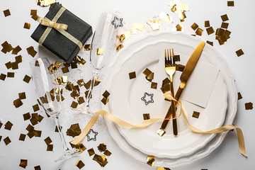 Beautiful tableware with Christmas gift box on white background