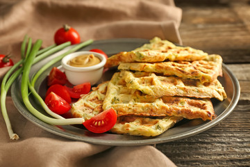 Metal tray with tasty squash waffles and sauce on wooden table