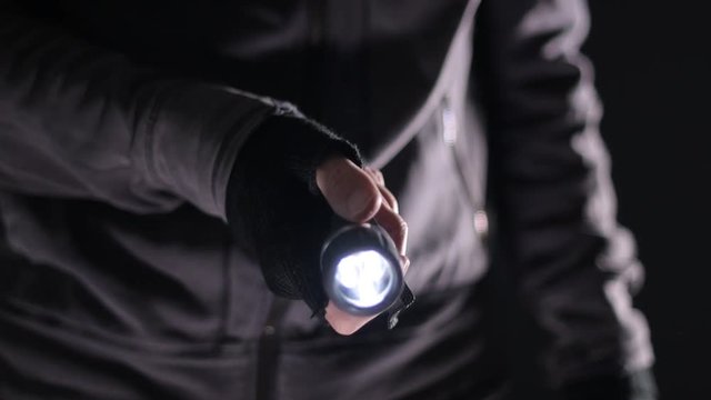 Burglar intruder with flashlight torch at night, low key selective focus