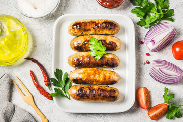 Grilled sausages with sauce vegetables and herbs. Top view, space for text.