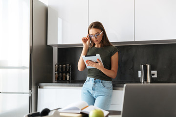 Beautiful young woman standing at the kitchen