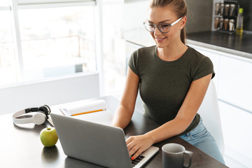 Smiling young woman sitting at the kitchen