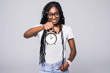 Portrait of a happy young afro american woman showing alarm clock isolated over gray background