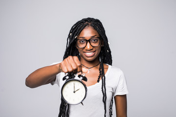 Portrait of a happy young afro american woman showing alarm clock isolated over gray background
