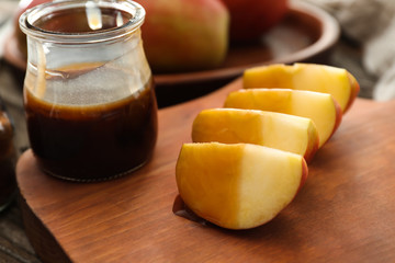 Apple wedges and sauce in jar on wooden board