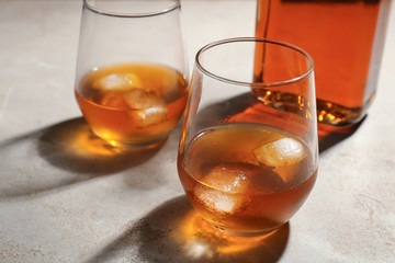 Glasses and bottle of whiskey on grey table