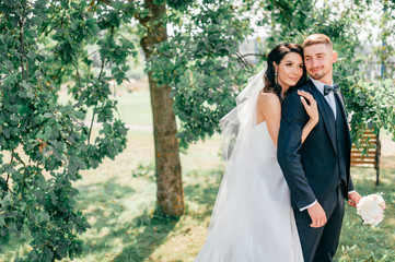 Beautiful wedding couple outdoor portrait. Young pretty bride hugging groom at nature.  Fine art...